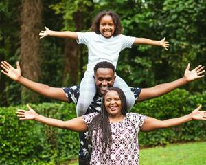 A family stands together, smiling with arms stretched open